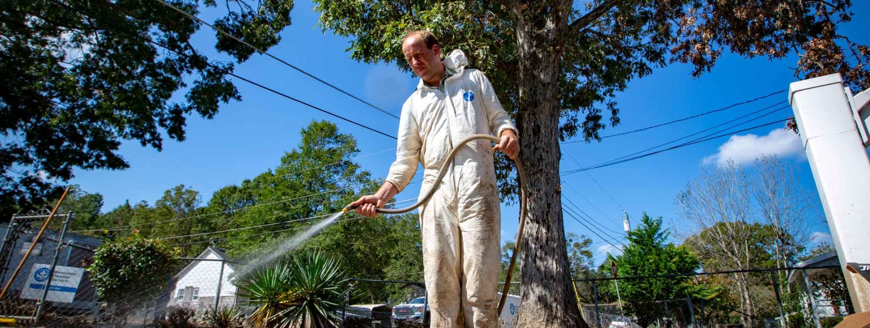 A man sprays off concrete to clean up the dirt left by flood water.