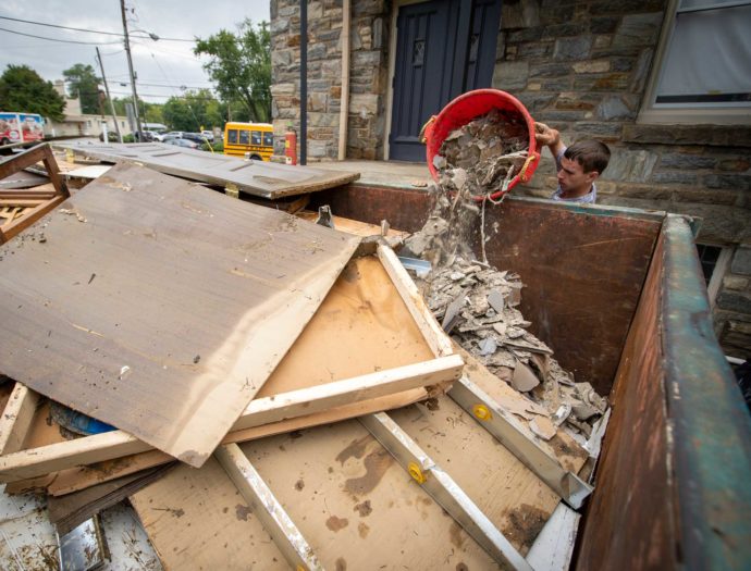 A man dumps debris into a dumpster in front of a church.
