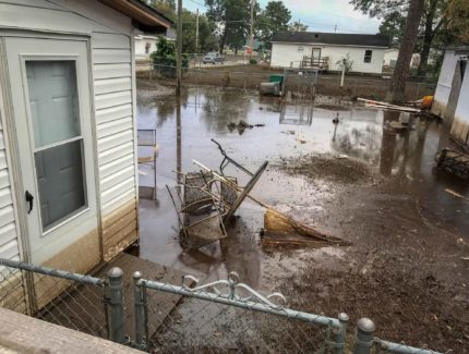 The back yard of a house with water and debris.