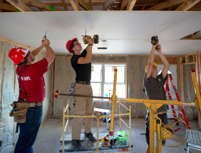 Three young people drilling the ceiling into a home.
