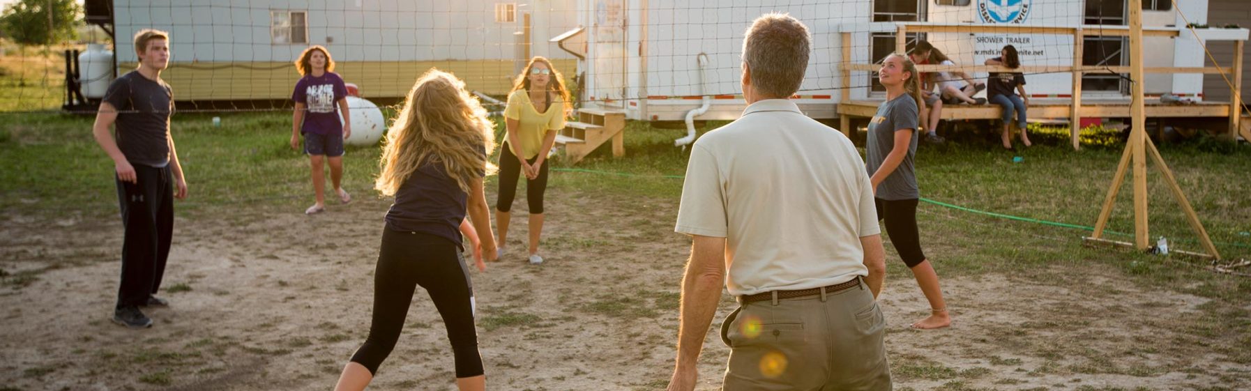 Photo of volunteers playing volleyball at sunset.