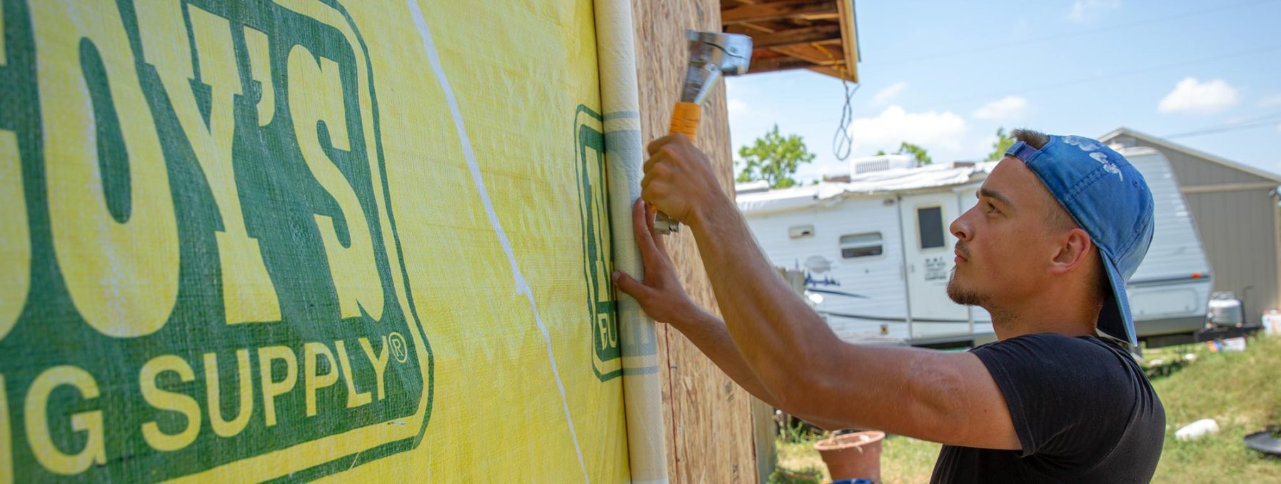 Photo of a young adult MDS volunteer installing house wrap on a recent project.