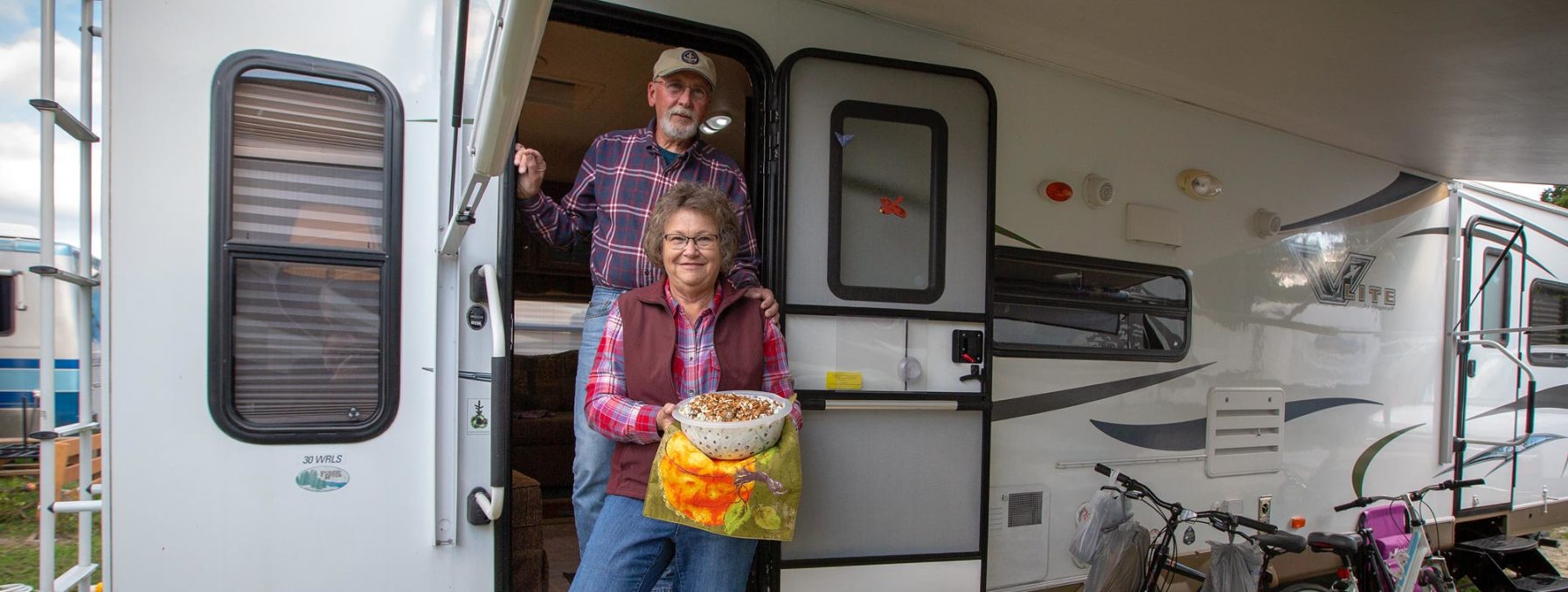 Two RV volunteers holding foot outside of their RV.