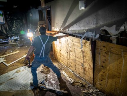 Photo of volunteers tearing out plywood in a church basement.