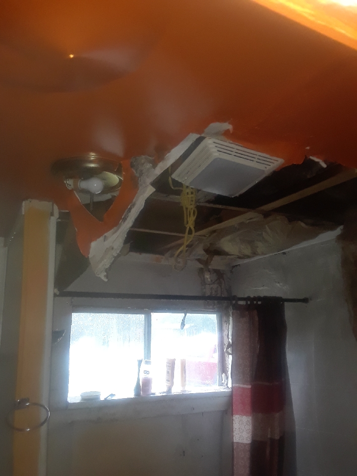 A ceiling that is damaged and is collapsing into the house.