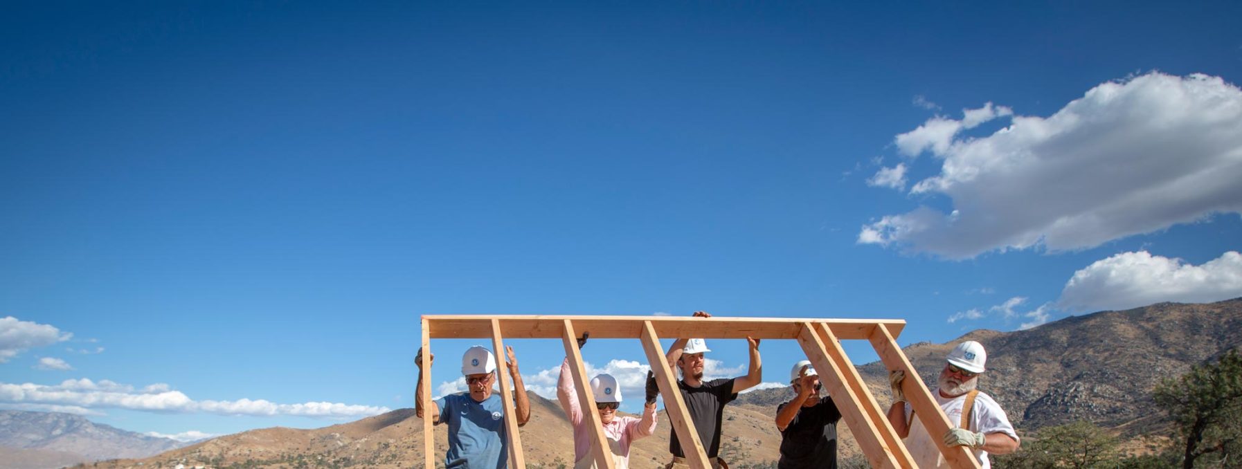 Five volunteers raising a house wall