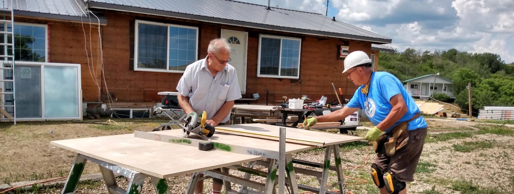 Photo of two volunteers working on siding at Westlake Bible Camp.