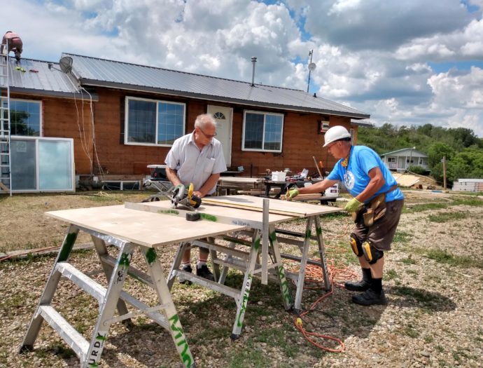 Photo of two volunteers working on siding at Westlake Bible Camp.