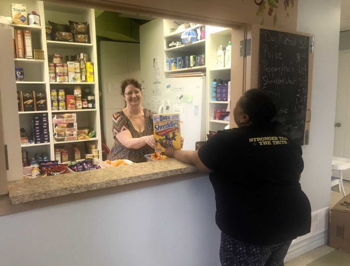 A photo of a food pantry worker handing box of food to a client.