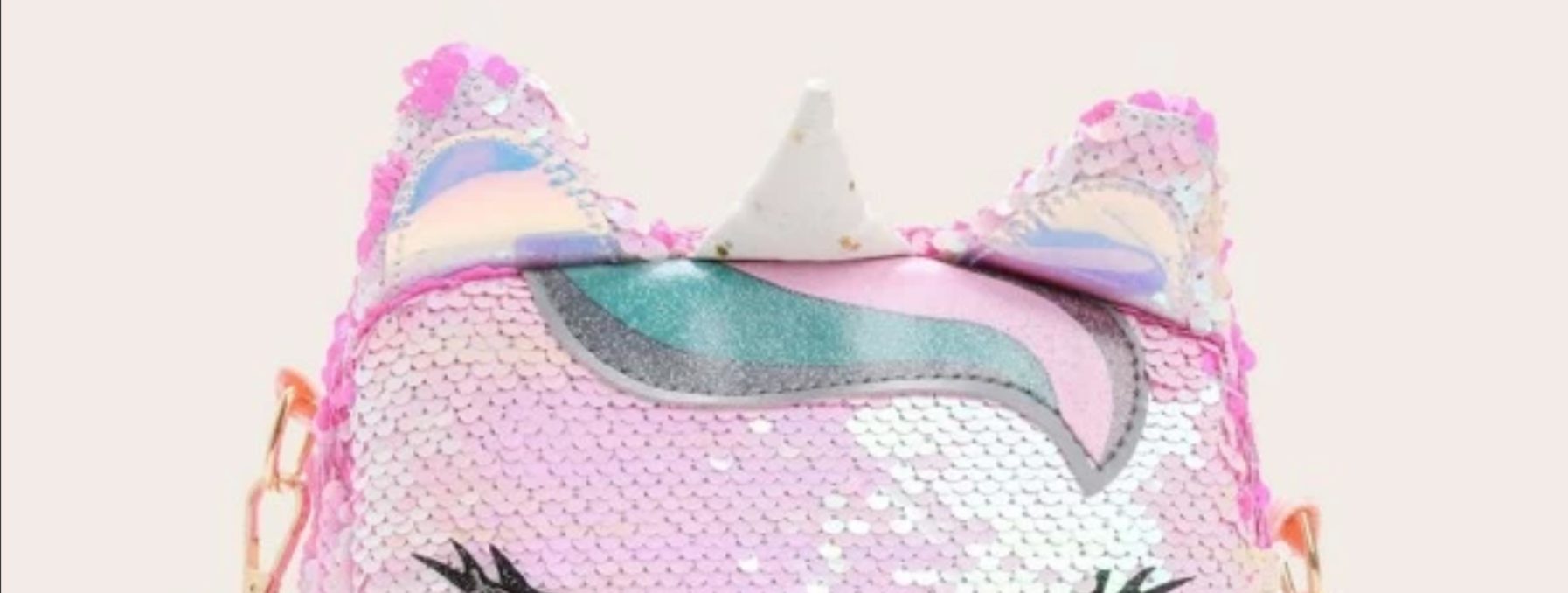 A photo of a pink sequined purse in the shape of a unicorn's head.