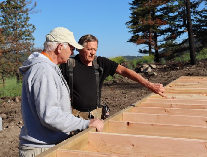 Monte Lake, volunteers work with lumber outdoors.