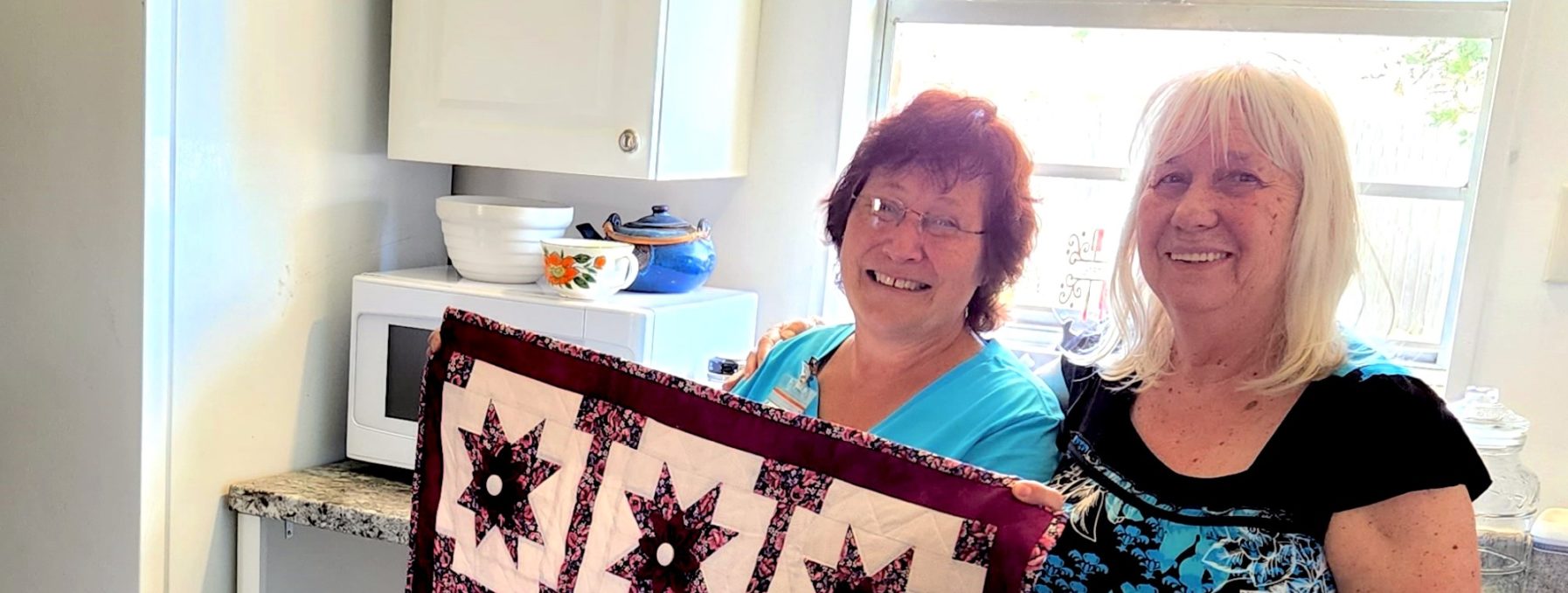 Two women photographed with quilted wall hanging to celebrate the completion of an MDS project in Marianna, FL