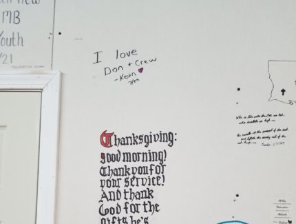 Text and art on a wall within a cook's space in Jennings, LA