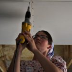 Paradise volunteer using a drill to mount drywall
