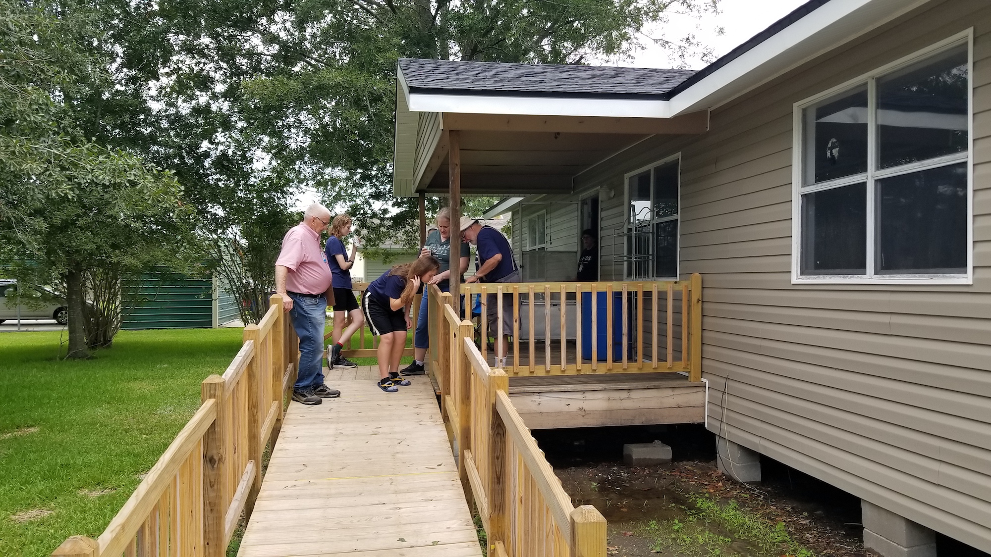 Volunteers inspect a wooden ramp leading to a home in Welsh that is being finished up with repairs
