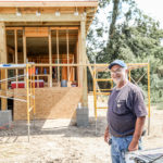 Longterm volunteer standing in front of a home that is being built for Shirley Zeno