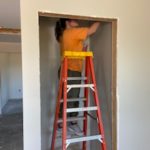 Volunteer in paradise working on interior finishes of a new build on a ladder in a closet