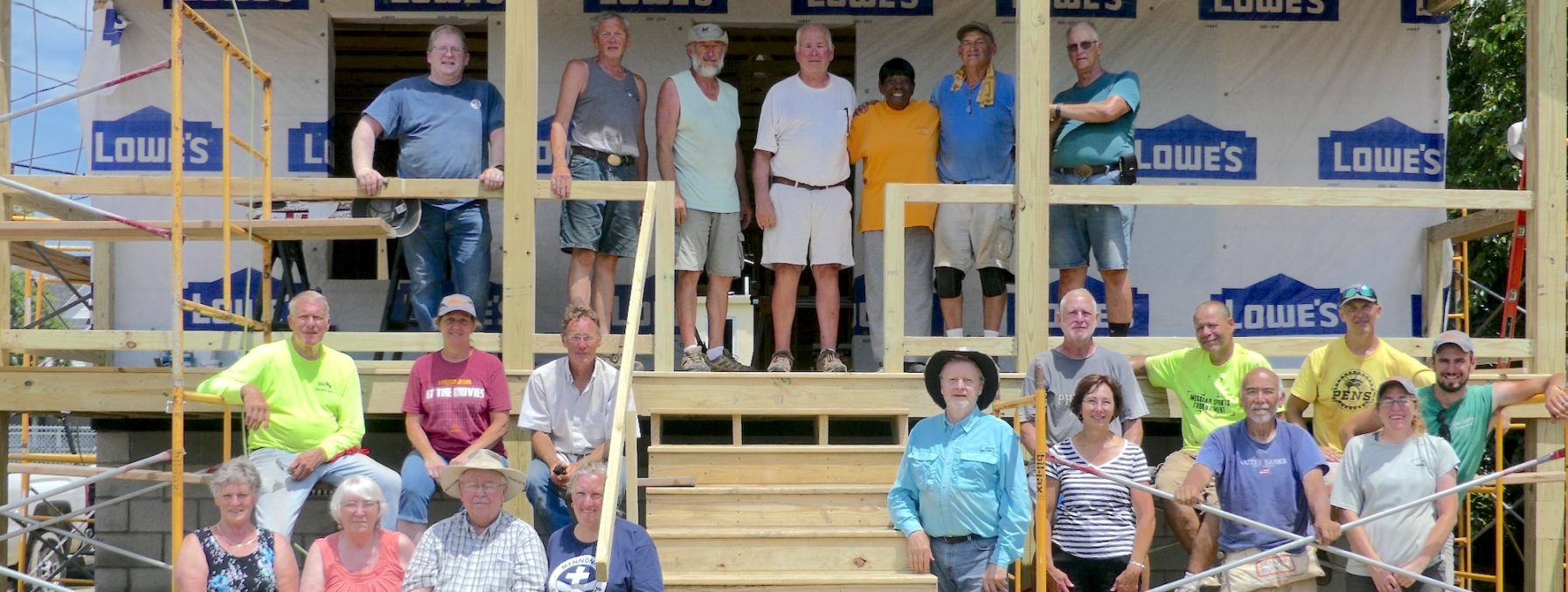 Volunteers in Crisfield pose for a group image in front of a new build with the homeowner standing at the top of the stairs
