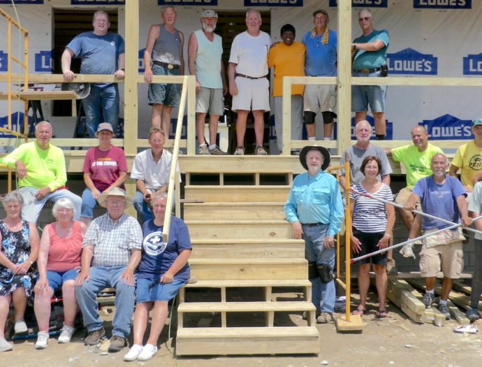Volunteers in Crisfield pose for a group image in front of a new build with the homeowner standing at the top of the stairs