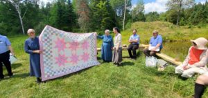 Women presenting a quilt to the new homeowners 