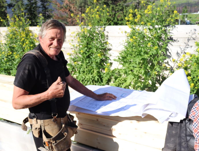 Rudy Martens giving a thumbs up next to plans for construction laid out for viewing