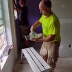 Todd Bomberger (yellow shirt, weekly volunteer) and Jonas Schmidt (black shirt, yearlong volunteer) working on drywall