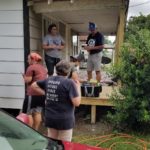 volunteers stand on a front porch that was made by a previous group of youth in Jennings