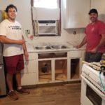 Volunteers pose for a photo inside of a kitchen with new furnishings.
