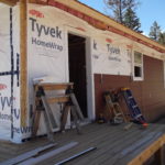 Photo of the exterior of a new build with siding being installed.