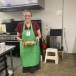 A volunteer by the name of Dianne is serving food as she stands in the kitchen