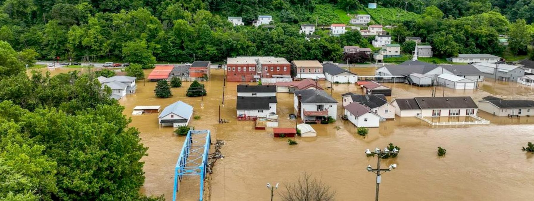 Homes and buildings of a town are severely foooding by standing water after 13 inches of rain fell in eastern Kentucky. Lush trees are in the background