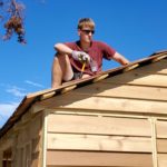 a volunteer sits on a roof, taking a break from roofing