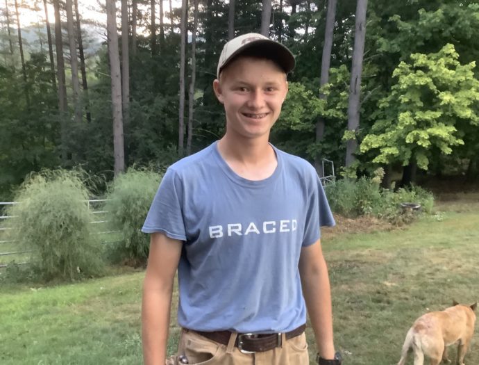 Isaac Visser poses for a picture with a shirt that reads "Braced"