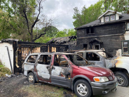 Severe fire damage at the Reimer property includes burnt structure and van