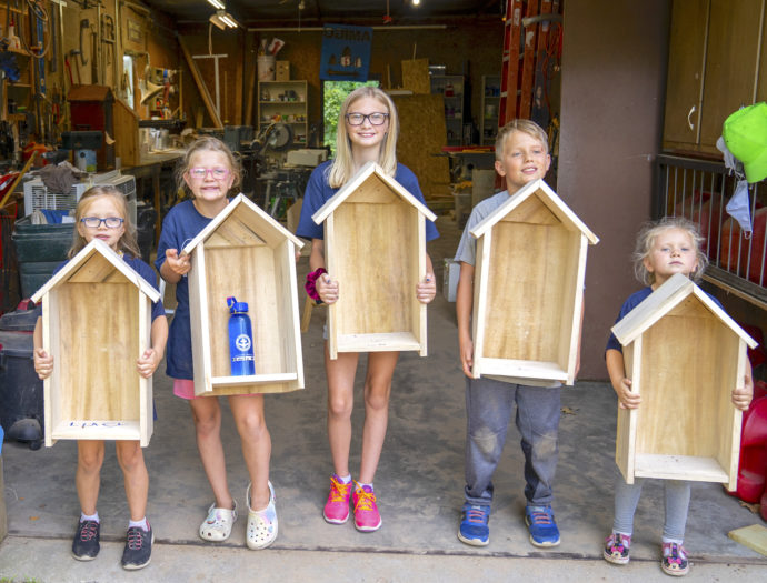 Young youth hold up wooden projects that were created during family volunteering at Amigo Centre