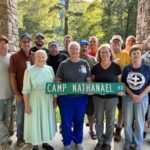 Group phots holding a street sign outdoors. Group Photo: L-R: Chad Kutzli, Ken Wolf, Forest Stuckey, Erma Wenger, Kirby Smith, LaRay Wise, Rita Wolf, Phil Stuckey, Fred Hershey, Jill Wyse, Terry Swearingen, Wesley Groff, Lou Pirozzi-Erb, Joetta Schlabach