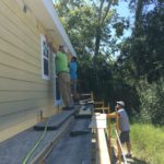 Volunteers in Jennings standing on an elevated platform working on siding and windows