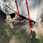 Bright red jacks lift a home for foundation work