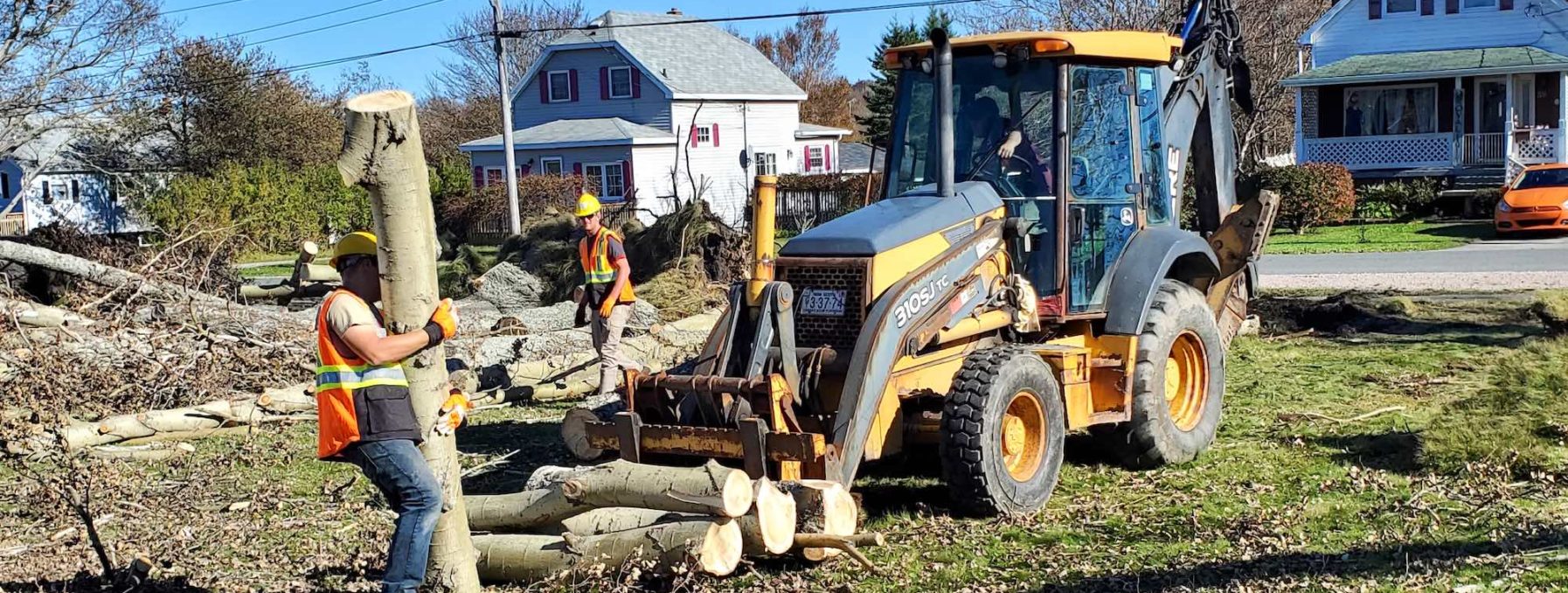 Volunteers move cut up trees with a front end loader in Nova Scotia