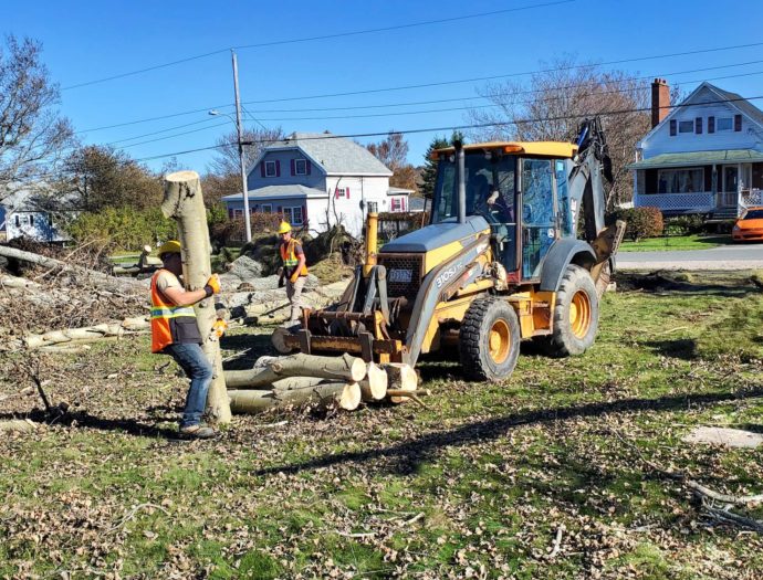 Volunteers move cut up trees with a front end loader in Nova Scotia