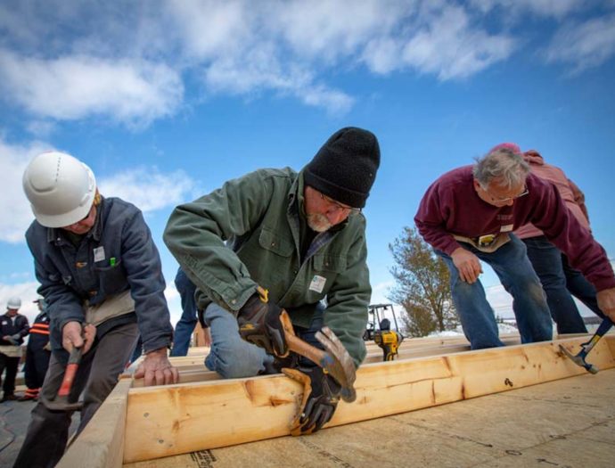 Volunteers cutting lumber outdoors on a cold day