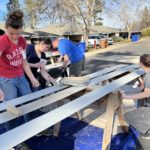 Volunteers from Canada paint trim or siding outdoors in Paradise
