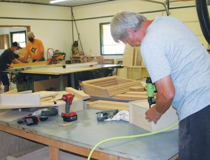 Photo of volunteers constructing kitchen and bathroom cabinets inside the MDS Cabinet Shop in Goessel, Kansas.