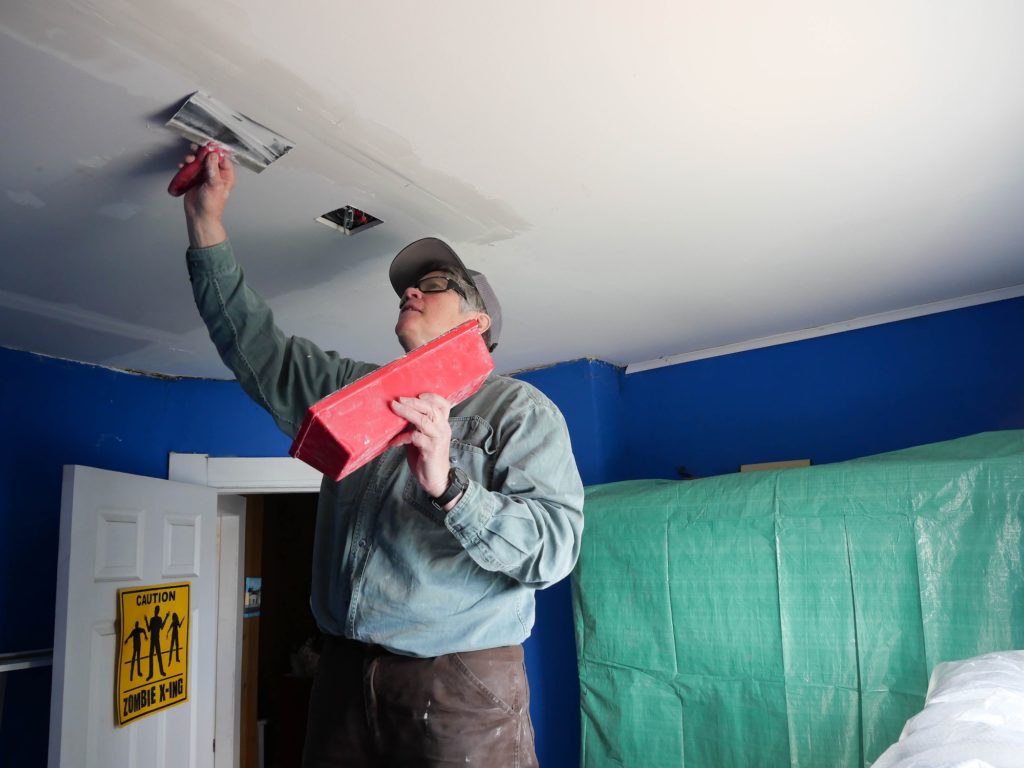 Crew leader Jan Joyce mudding a ceiling.