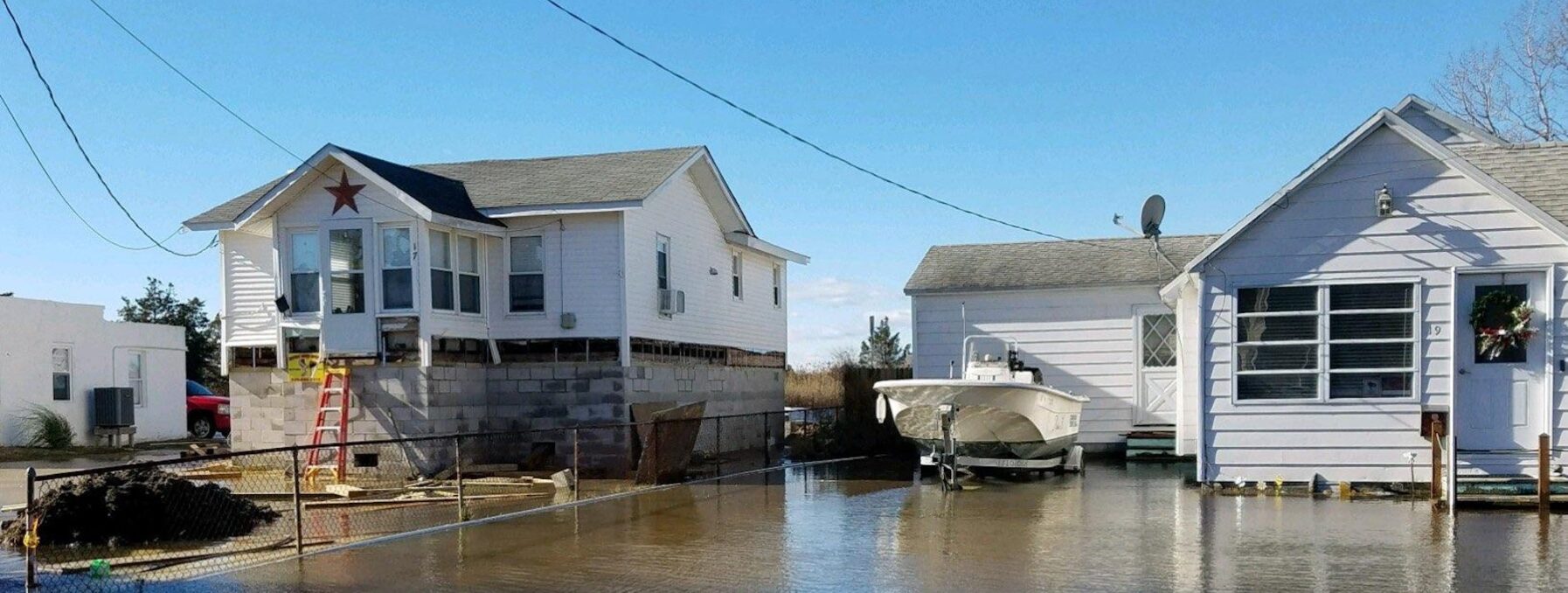 An elevated home in Crisfield, MD next to a home that sits in water that has not been lifted.