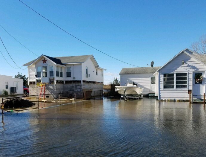An elevated home in Crisfield, MD next to a home that sits in water that has not been lifted.