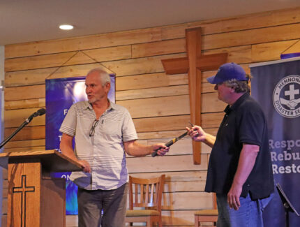 In a symbolic gesture, Peter Thiessen, MDS Shuswap Response Coordinator, passes a hammer on to Wes Janzen, a North Shuswap Christian Fellowship elder at the closing celebration of this MDS response. MDS photo/Nikki Hamm Gwala