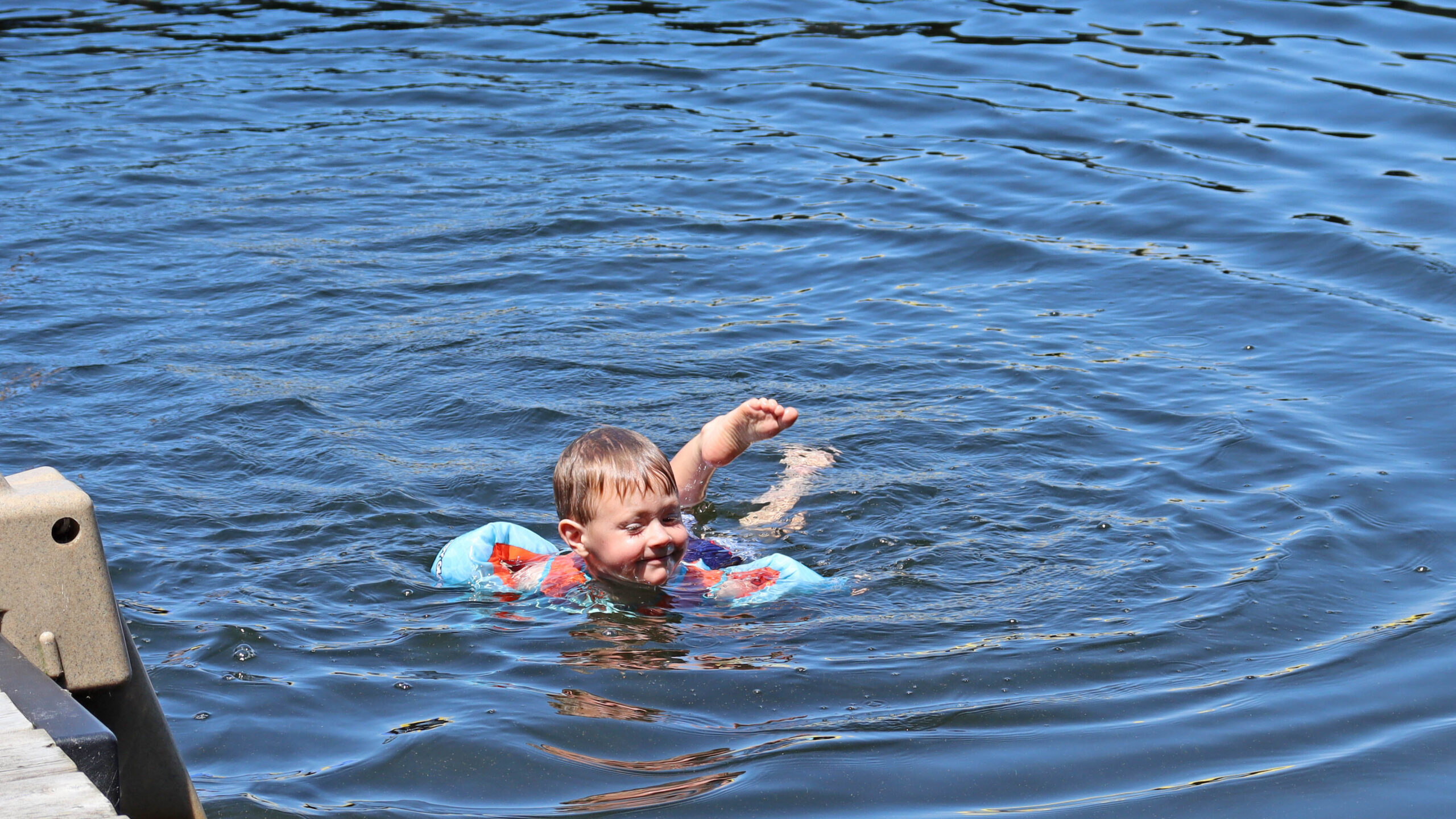 A young boy swims in a lake