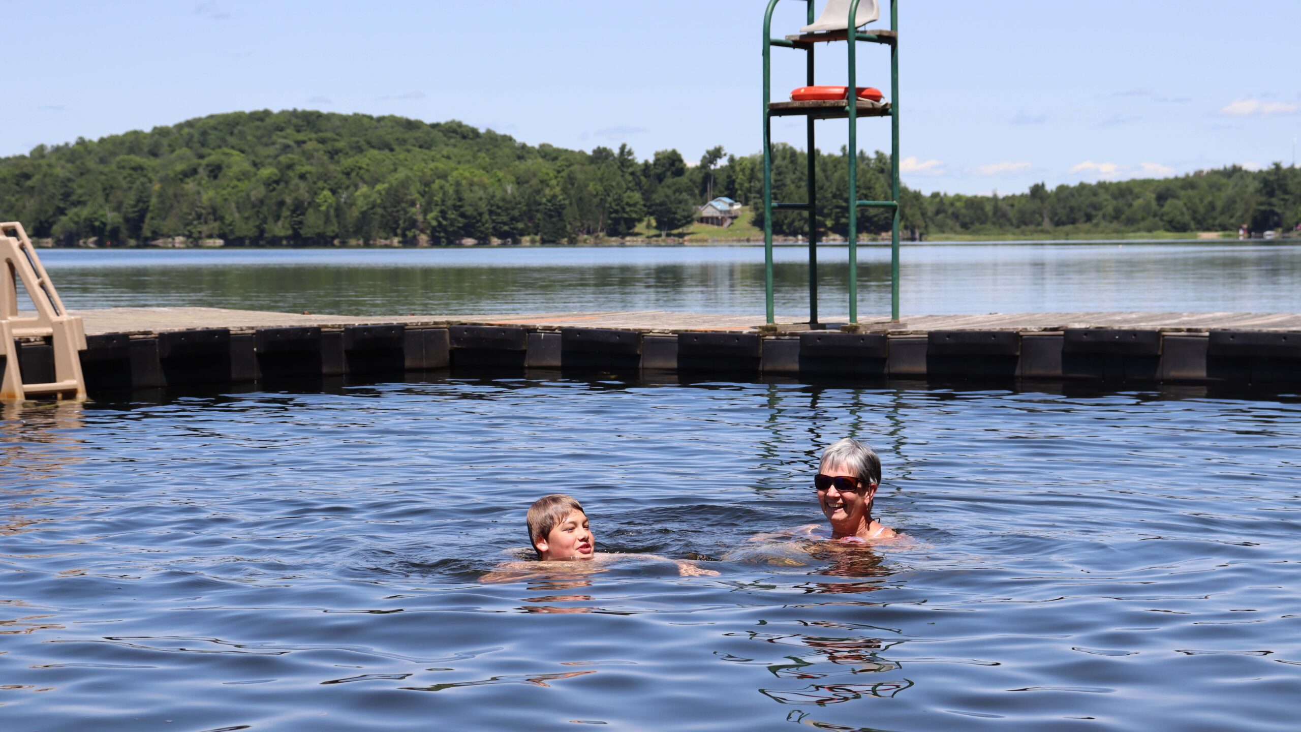 A grandmother and grandson swim in a lake