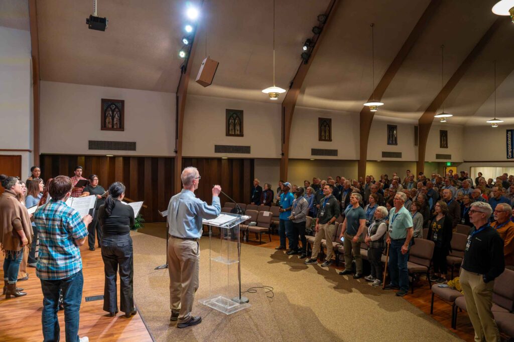 Image of MDS staff, volunteers, and supporters worshiping together in a church sanctuary